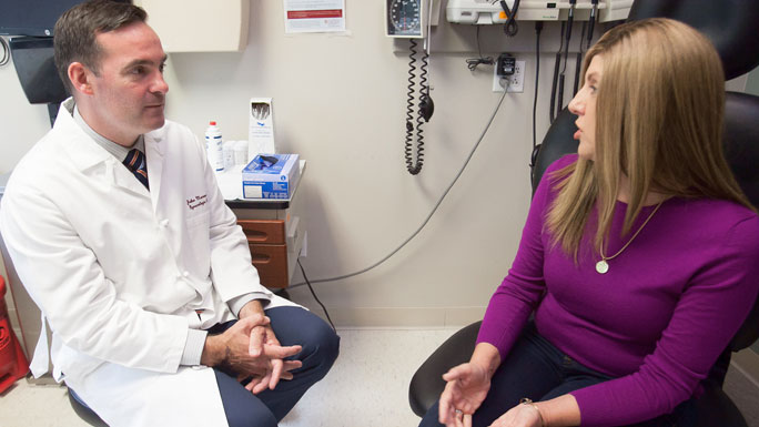 Gynecologic oncologist John Moroney, MD, speaks with a patient in clinic