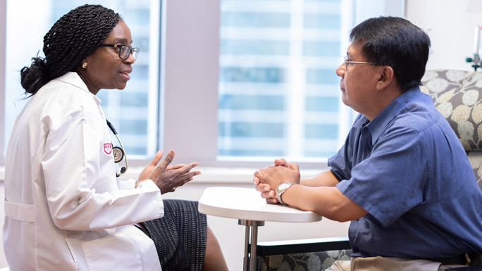 Olatoyosi Odenike, MD, meeting with a man in clinic