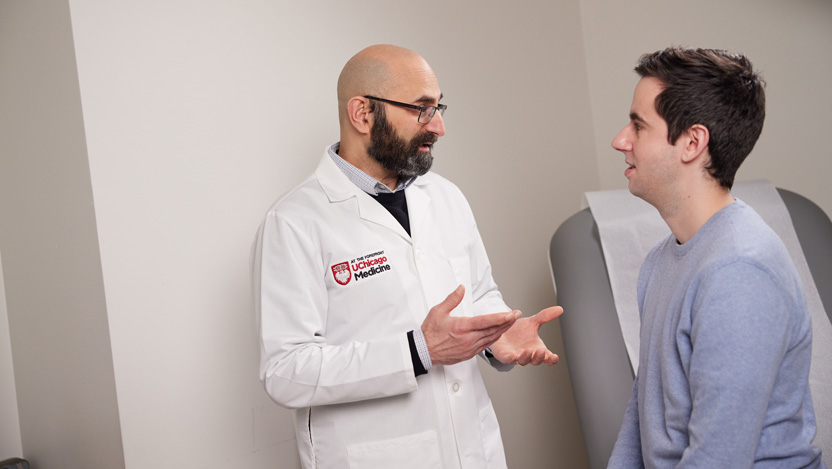 Neurologist Naoum Issa, MD talking with a male patient in doctors office