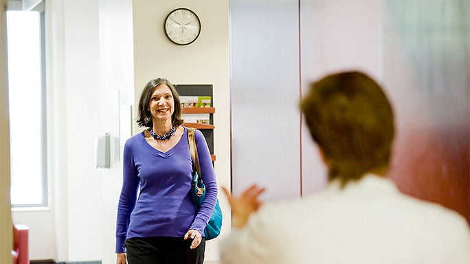 “Woman greeted by staff member while walking from waiting room