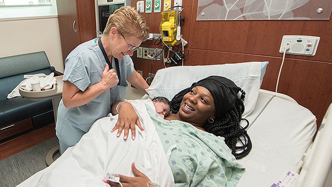 Certified nurse midwife Wendy Allen, MSN, APN, CNM, talking to a mom with her newborn at bedside