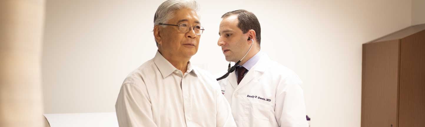 Randy Sweis, MD, examining patient with stethoscope