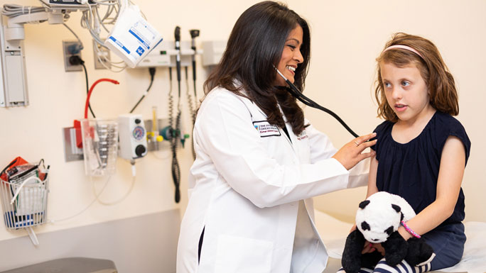 Ami Desai, MD, examining little girl