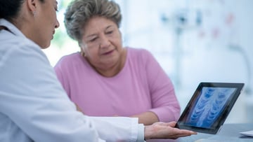 Female doctor showing lung scan to older female patient