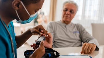 Male nurse uses glucose monitor on patient