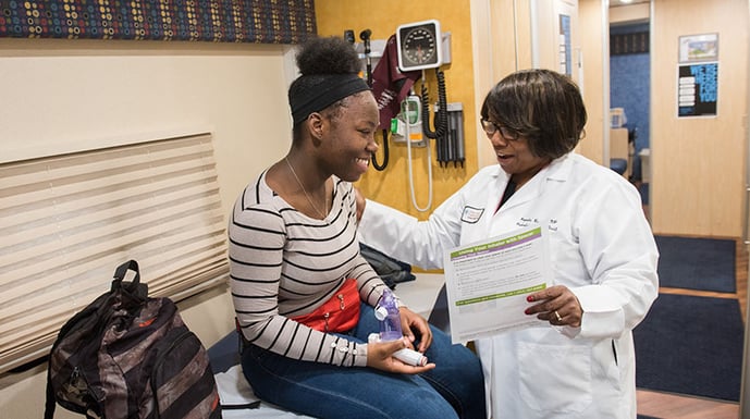 Doctor with teenage patient holding asthma inhaler
