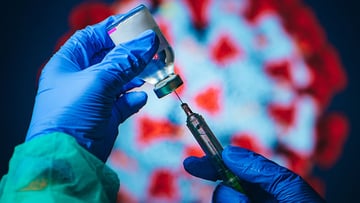 Gloved hands holding COVID-19 vaccine