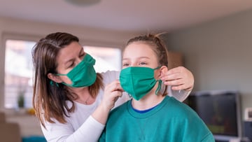 adult fitting face mask to young person