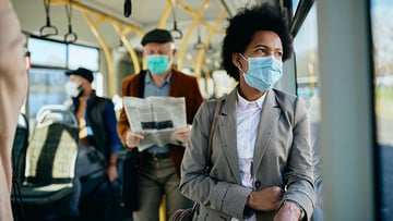 Pensive black businesswoman with face mask commuting by public transport