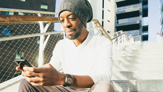 A person sitting down using his smartphone.