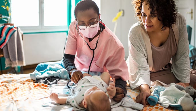 Masked nurse with newborn and mom during in-home visit