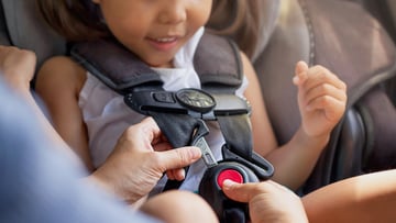 A child being buckled into a car seat.