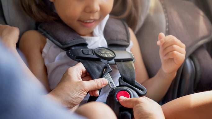 A child being buckled into a car seat.