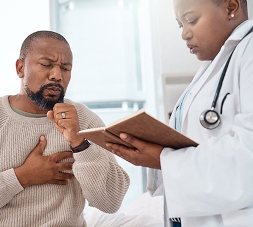 Pulmonary fibrosis patient grabbing chest while doctor consults with them