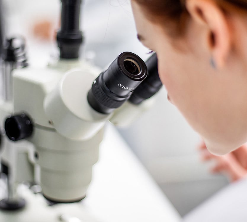 A scientist looking into a microscope.