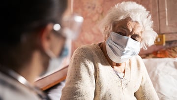 Female doctor doing medical exam of a senior woman at her home.