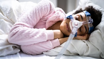 Person sleeping wearing CPAP machine