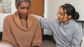 Grieving woman in support group with other woman offering support