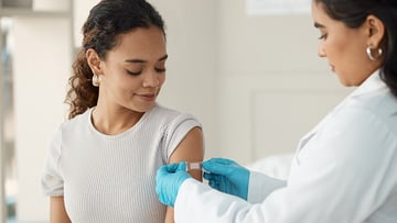 Health provider putting a bandaid on a woman