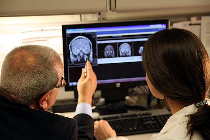 Neurosurgeon and HHT expert Dr. Issam Awad reviewing a neurovascular malformation on a brain scan with program coordinator Shannon Love