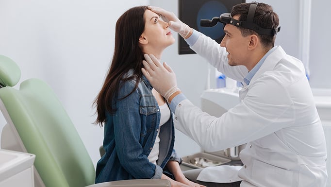 ENT checking nose of his female patient