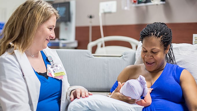 Lacation consultant observes mother breastfeeding newborn girl