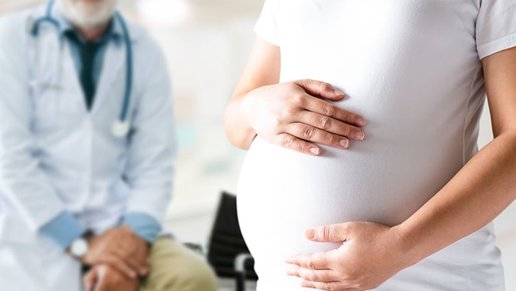 Torso of pregnant patient with doctor in the background