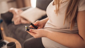Torso of pregnant person checking blood sugar