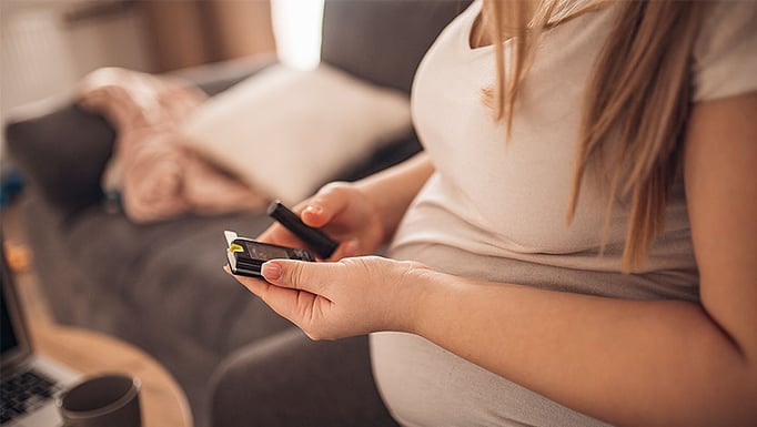 Torso of pregnant person checking blood sugar