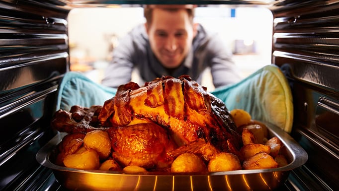 A man putting a thanksgiving turkey in the oven