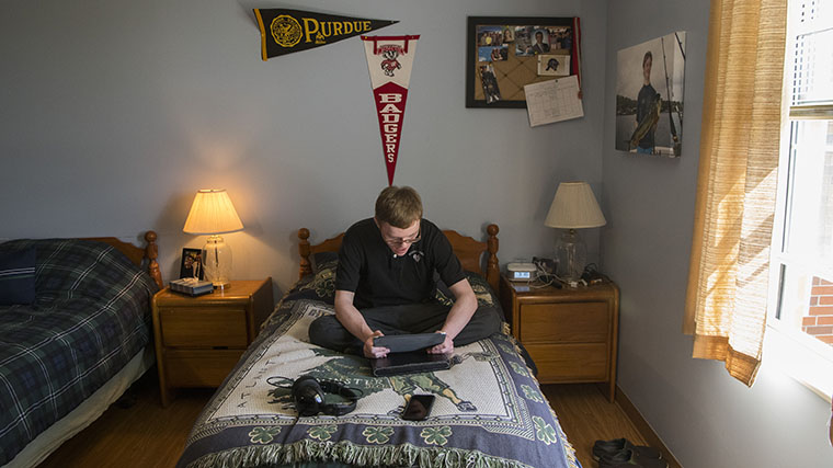 Image of a Misericordia resident in his bedroom looking at a photo in his hands
