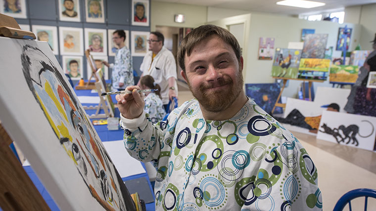 Image of a smiling Misericordia resident painting