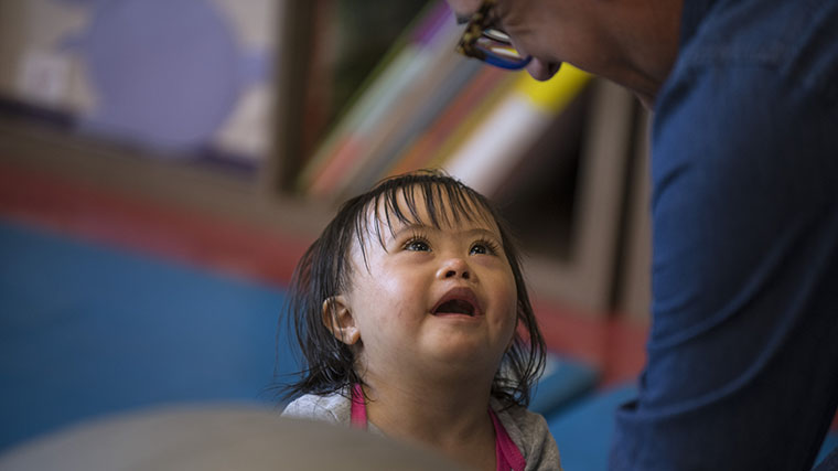 Image of a young Misericordia resident looking up at a staff member