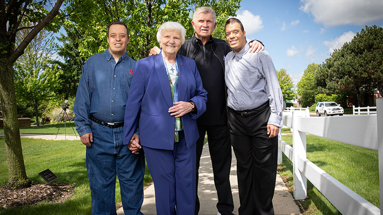 Mike Ditka standing with Misericordia Executive Director Sister Rosemary Connelly and two residents