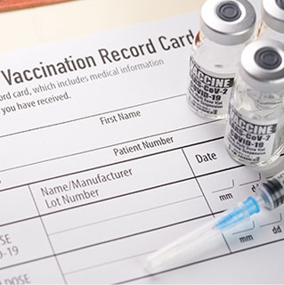 COVID-19 vaccination record card with vaccine viles and needle