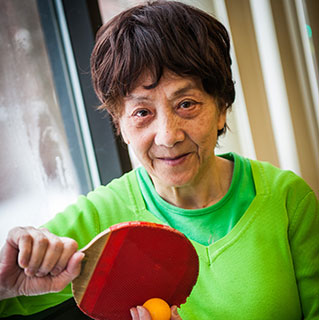 Parkinson's disease patient Cheng Xiu Xu, who was treated by physicians Tao Xie, MD, PhD, and Peter Warnke, MD, plays ping pong at her apartment building