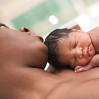 Mother cradling newborn skin to skin