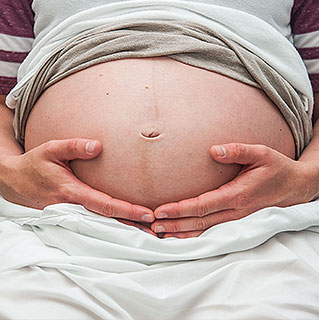 Woman's hands cupping bare pregnant belly