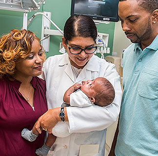 Maternal-fetal medicine specialist Dr. Sarosh Rana holding a newborn with his parents at her side