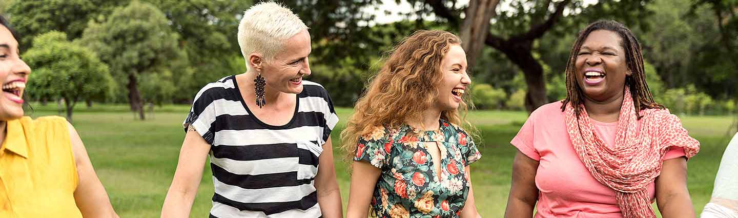 Three women walking and laughing together outdoors