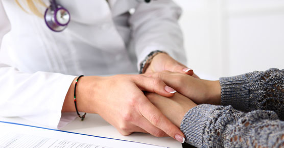 Image of caregiver holding patient's hands, supportive oncology