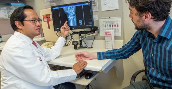 Jovito Angeles, MD, with male patient in clinic room
