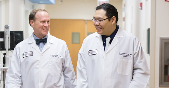 Pediatric neurologists Dr. Douglas Nordli and Dr. Chalongchai Phitsanuwong talking while walking down a halfway