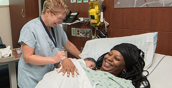 Certified nurse midwife Wendy Allen at the bedside with a mom and her newborn