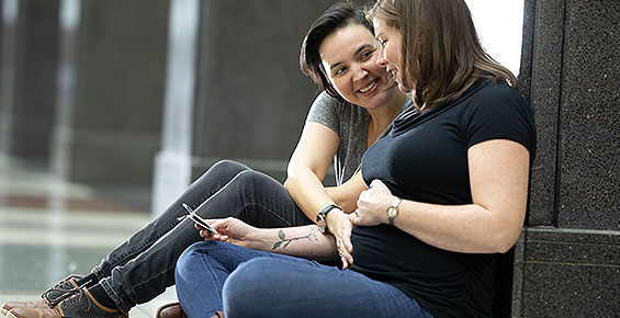 Woman looking at sonogram with partner's hand on baby bump