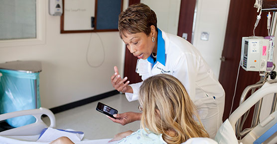 Brenda Garrett, MSN, MHA, shows pictures of her recovery to an unidentified patient, inside Mitchell Hospital on the UChicago campus