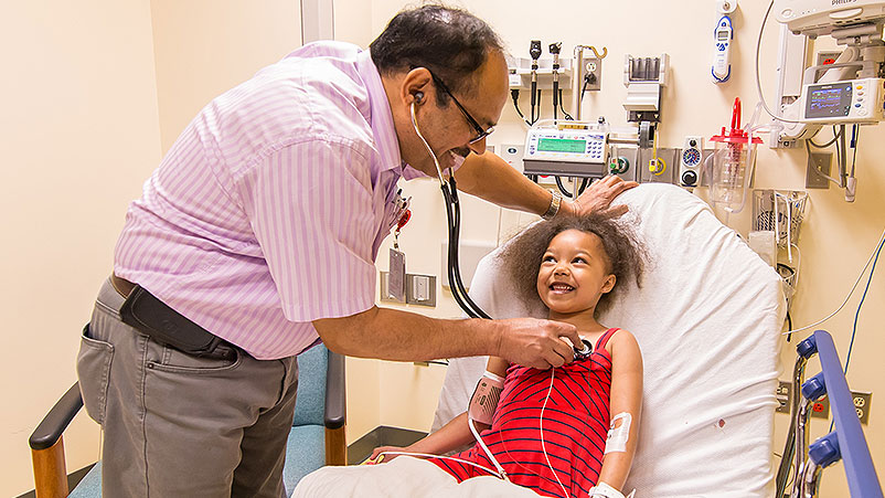 Pediatric cardiologist Umesh Dyamenahalli, MD, checks a giggling patient