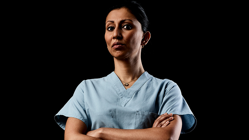 Doctor sitting on cabinet looking right, looking happy