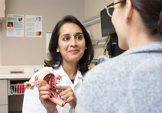 Obstetrician/gynecologist Maryam Siddiqui, MD, talking with a patient while pointing to a 3D model of female reproductive organs