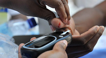 A patient pricking their finger for a diabetes blood sugar test